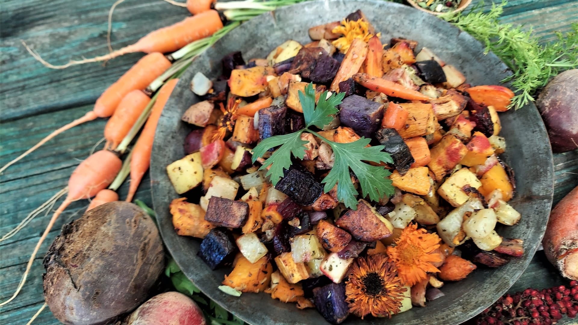 A colorful platter of roasted root vegetables with fresh vegetables around them
