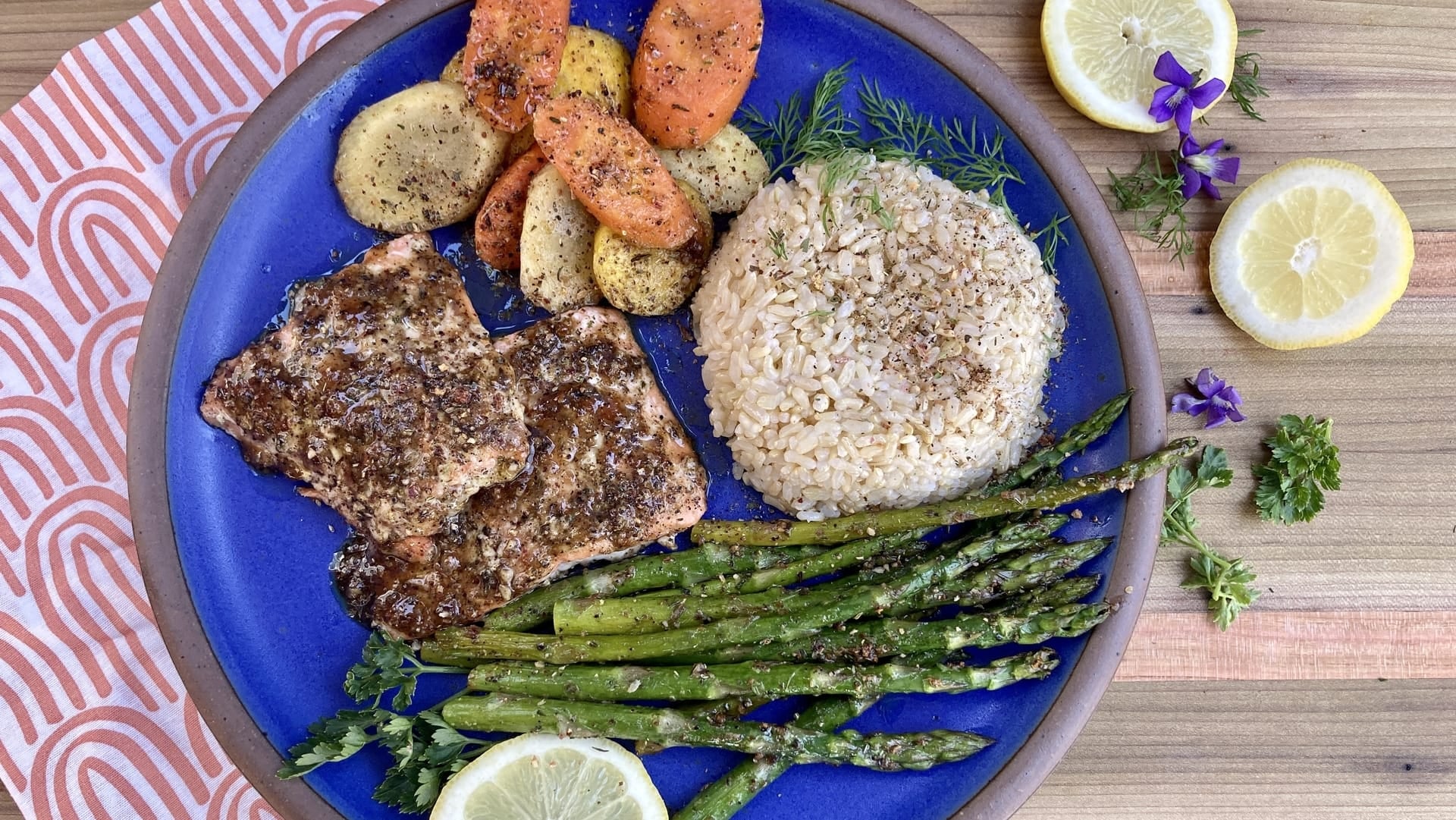 A blue plate of salmon, rice, asparagus, and carrots glazed and roasted with Well Seasoned Table Appalachian Lemon Seasoning.