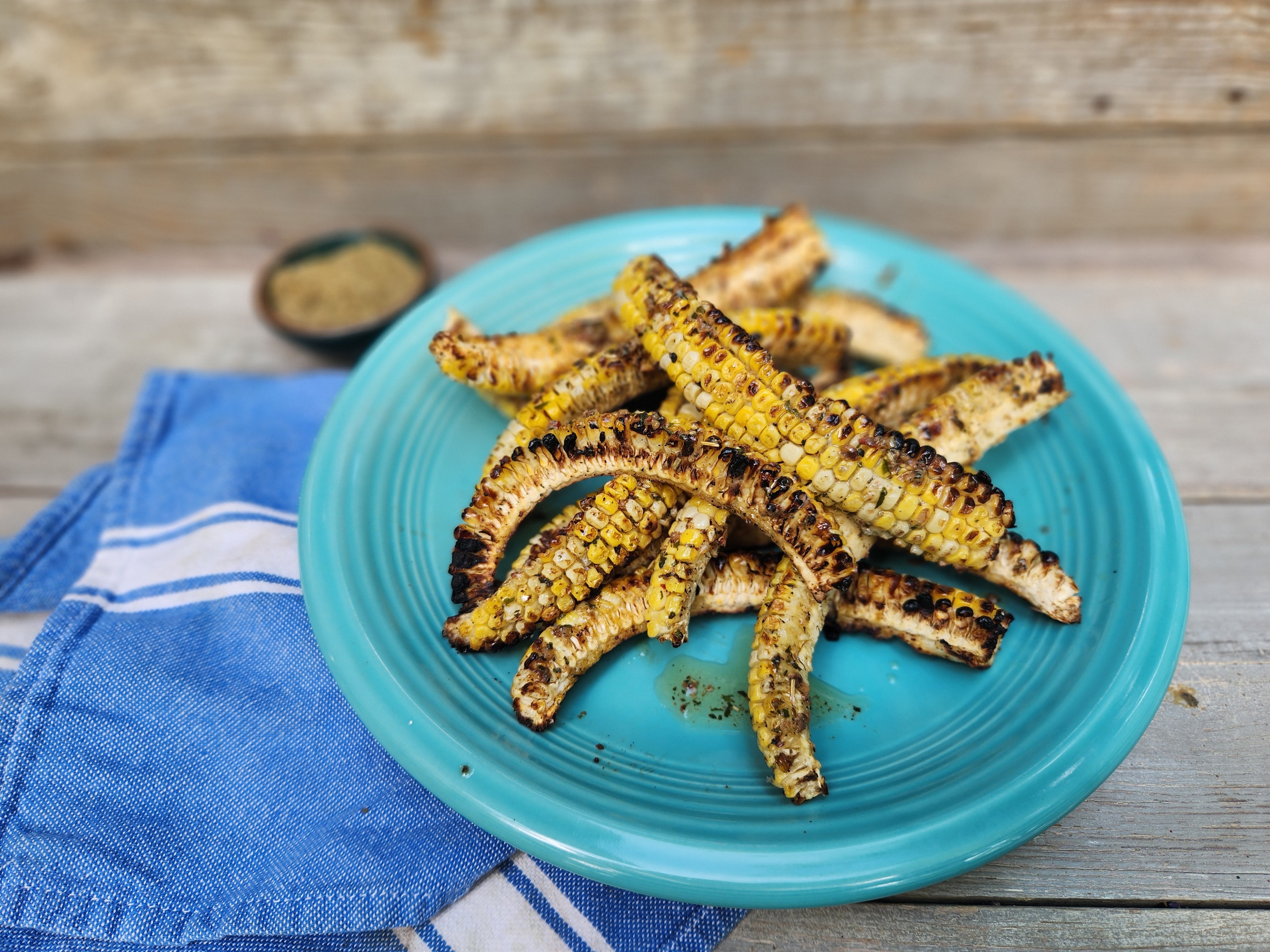 Grilled Corn Ribs on a bright turquoise blue plate with a blue napkin on a wood table