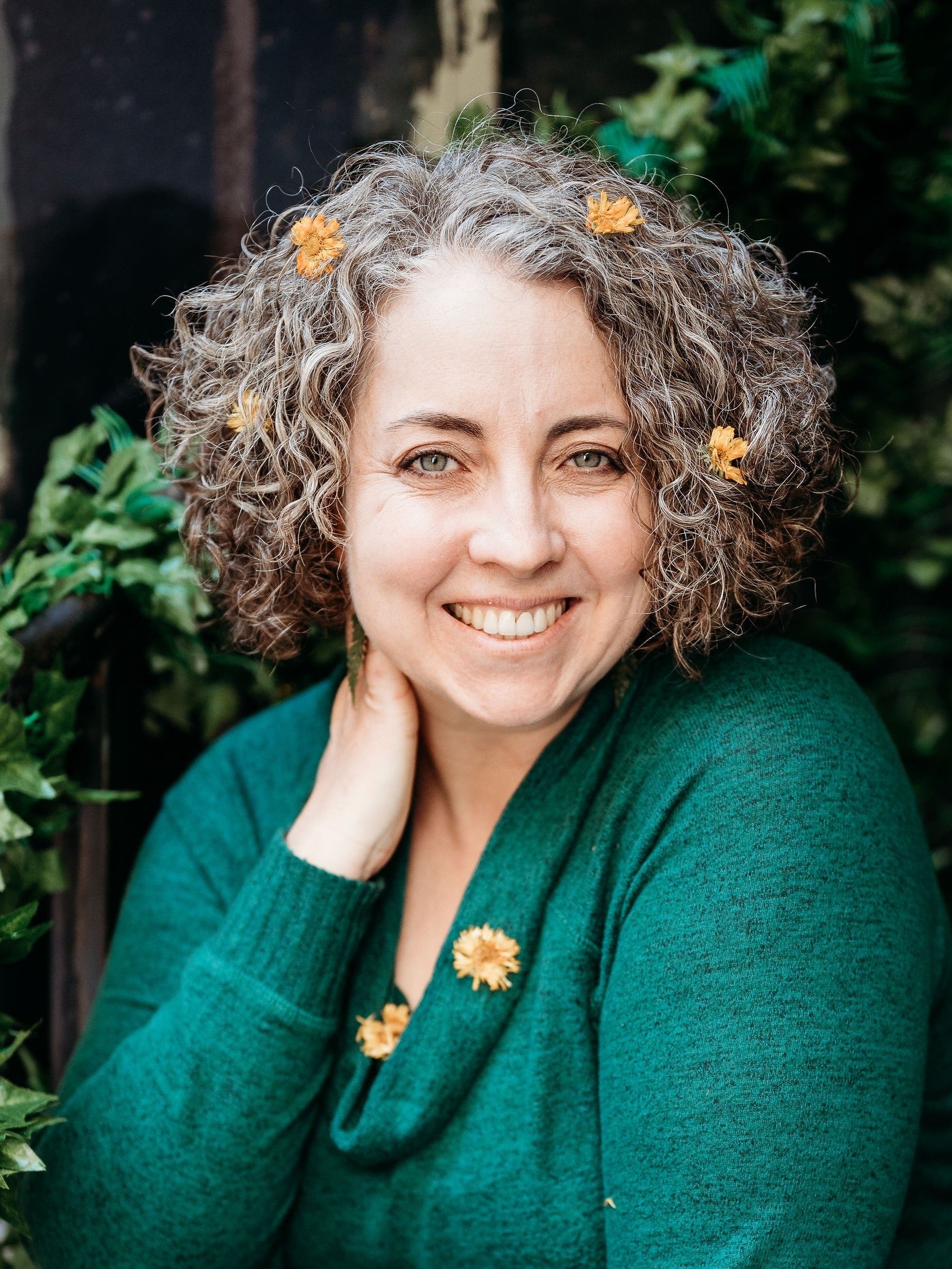 Portrait of the founder of Well Seasoned Table, Sarah Wickers. She is in a green shirt with orange flowers in her hair