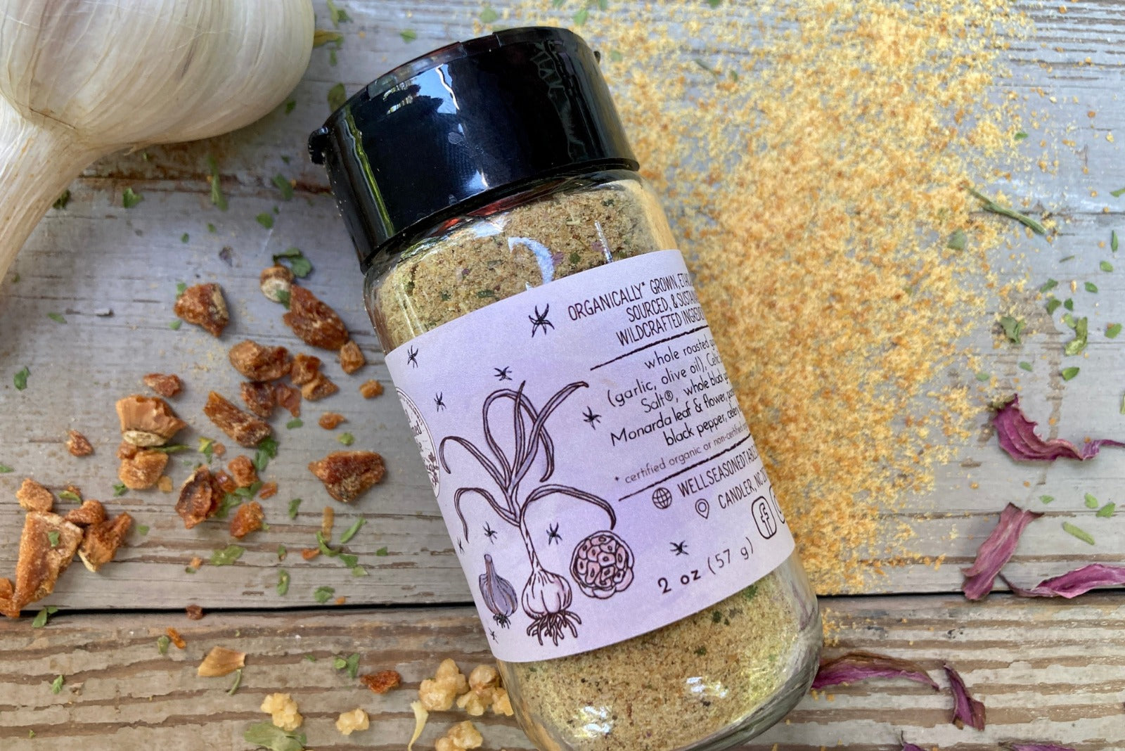 A glass jar of Magic Garlic Dust from Well Seasoned Table, a spice shop, on a wooden background.