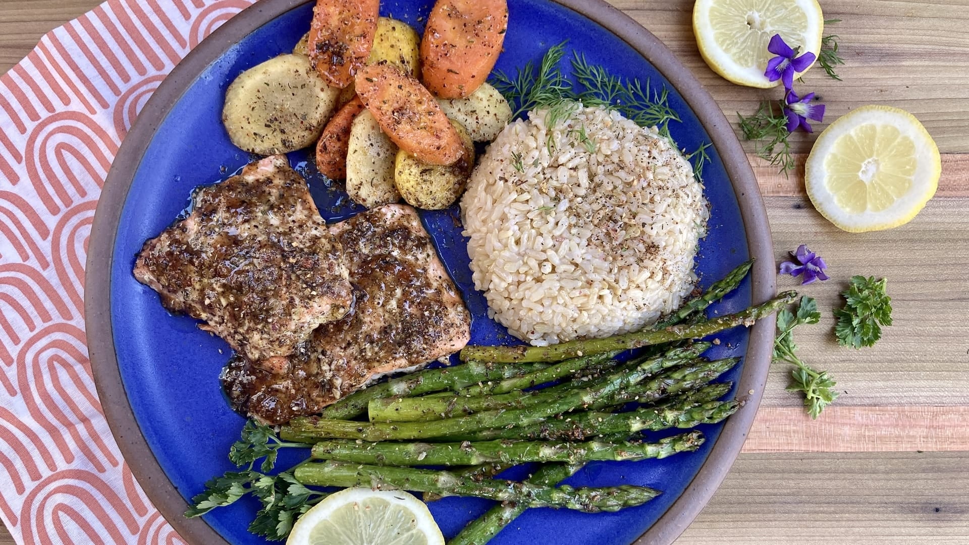 A blue plate of salmon, rice, asparagus, and carrots glazed and roasted with Well Seasoned Table Appalachian Lemon Seasoning. 