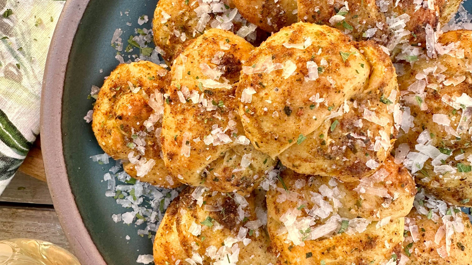 A ceramic plate of garlic knots covered in butter, Magic Garlic Dust, and herbs