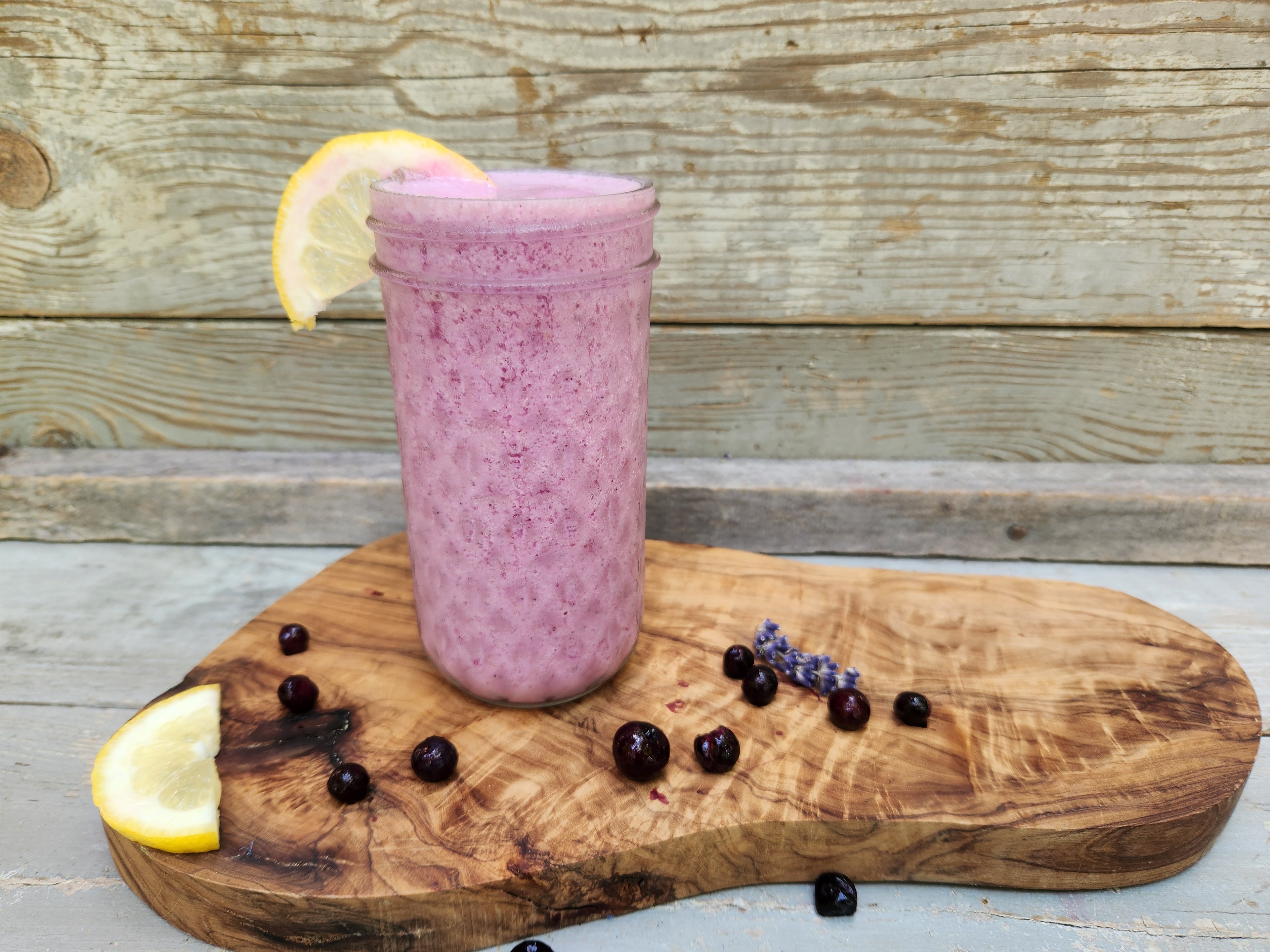 Blue Ridge Frozen Lemonade in a beveled glass on a Polished Wood Slab with blueberries and lemon