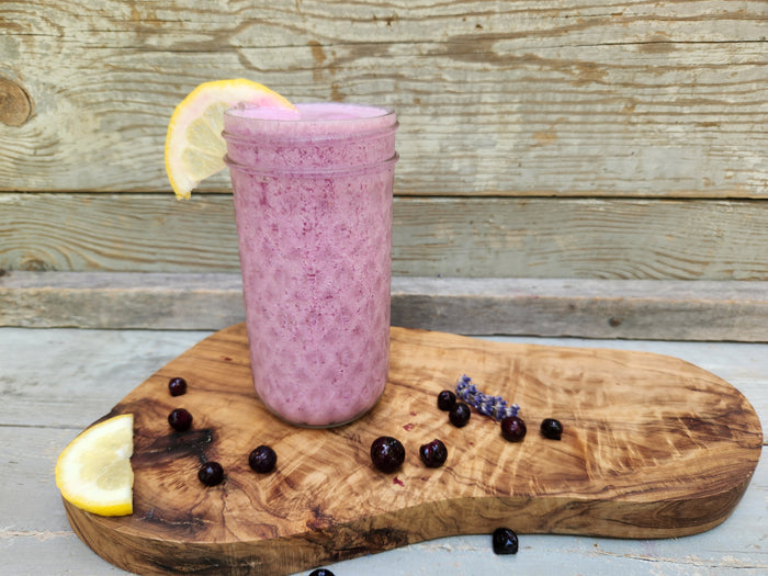 Blue Ridge Frozen Lemonade in a beveled glass on a Polished Wood Slab with blueberries and lemon