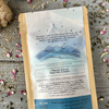The back of a packet of Evening Digest Tea from Well Seasoned Table on a wooden background with ginger, dried flowers, cinnamon, and herbs around it.