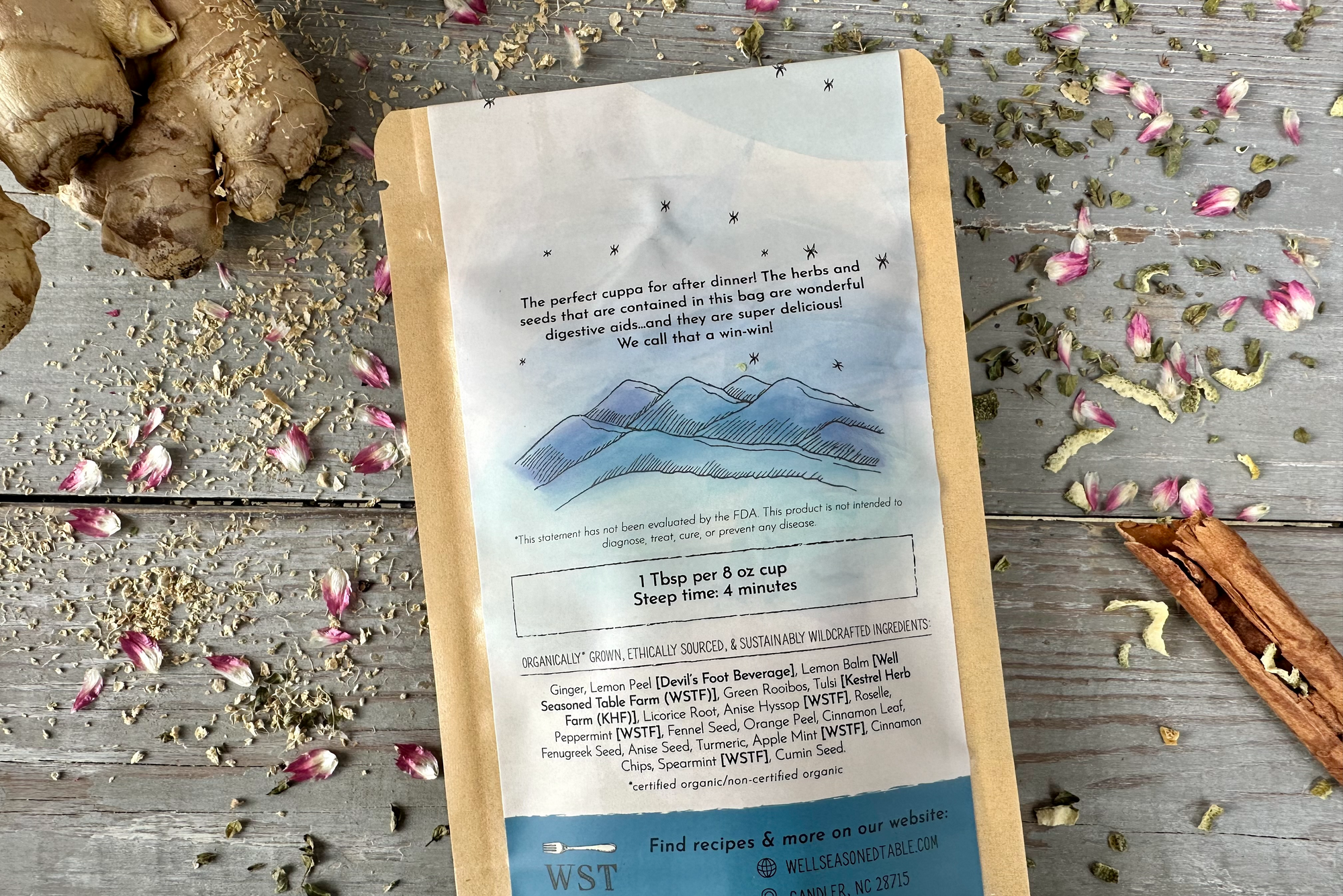 The back of a packet of Evening Digest Tea from Well Seasoned Table on a wooden background with ginger, dried flowers, cinnamon, and herbs around it.