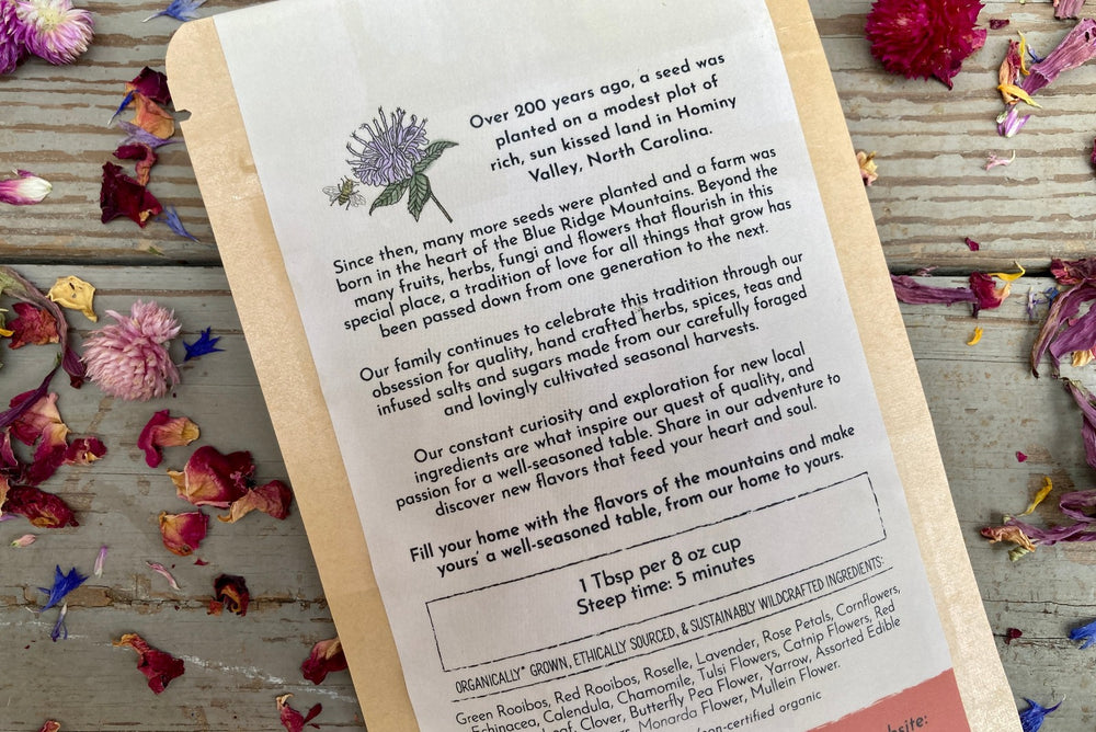 The back of a packet of Mountain Sunset Tea on a wooden background surrounded by colorful dried flowers.
