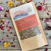 A packet of Mountain Sunset Tea on a wooden background surrounded by colorful dried flowers.