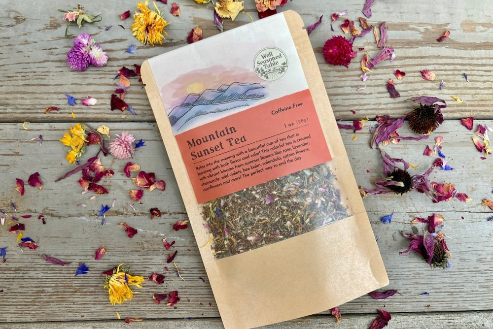 A packet of Mountain Sunset Tea on a wooden background surrounded by colorful dried flowers.